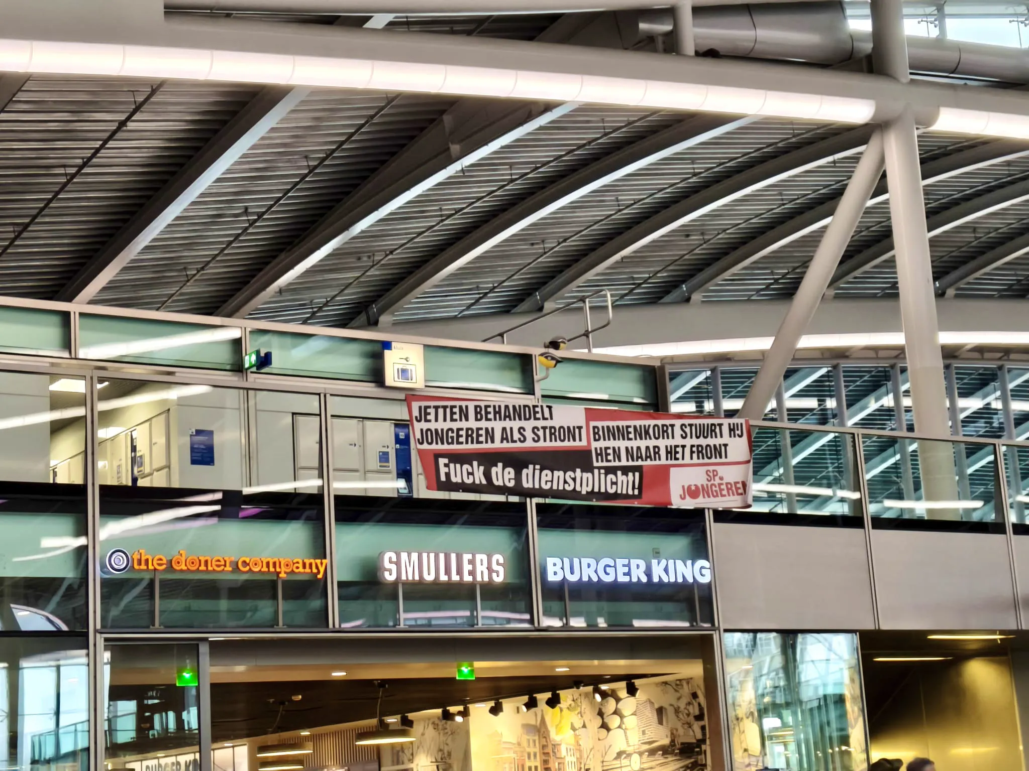 Jongeren hangen spandoek tegenover Defensie Pop-Up: ‘’Binnenkort stuurt Jetten jongeren naar het front’’.