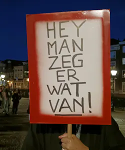 Een protestbord van een deelnemer aan de Protestmars Alkmaar breekt de stilte. Op het bord staat: Hey Man zeg er wat van!